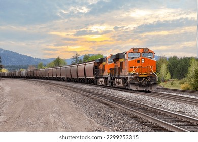 freight train with colorful sunset transporting cargo close to Whitefish, Montana in springtime