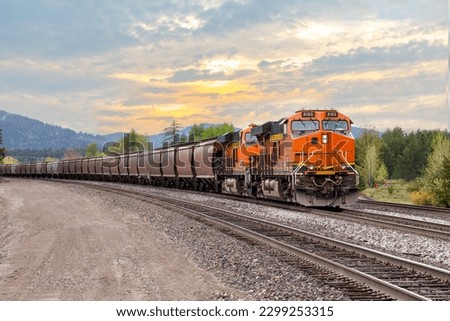 freight train with colorful sunset transporting cargo close to Whitefish, Montana in springtime