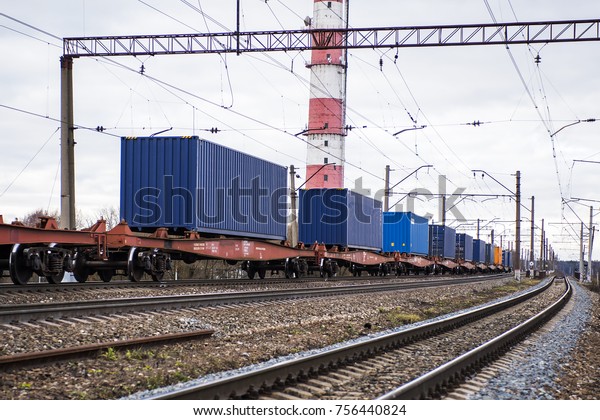 Freight train with containers on the platform is\
standing on the railroad\
tracks