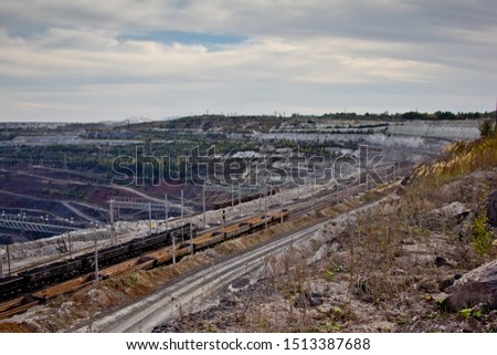 Freight train with ore in open mining quarry.