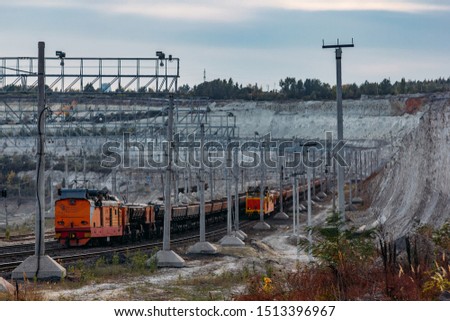 Freight train with ore in open mining quarry.