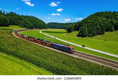 A freight train transports cars through the green valley in summer  Train ride railway track  Train railroad  Railroad train scene