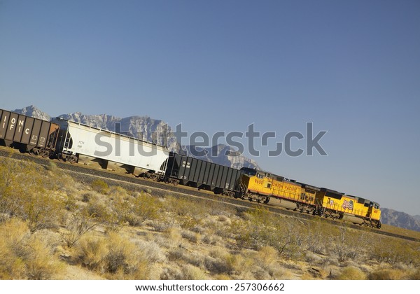 Freight train travels through\
desert and mountainous areas of Mojave Desert in Southern\
California