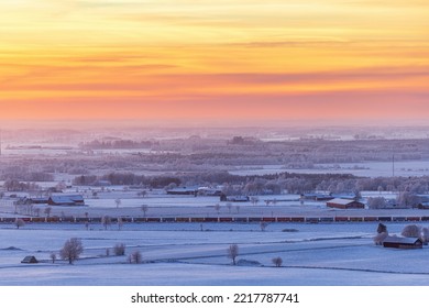 Freight Train In A Wintry Landscape With A Colorful Sunset