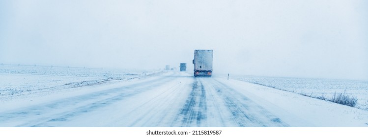 Freight transportation truck on the road in snow storm blizzard, bad weather conditions for transportation event, selective focus