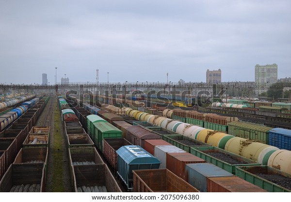 Freight wagons stand at the station on the\
railroad tracks, cargo transportation. Residential buildings in the\
distance