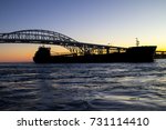 Freighter At International Blue Water Bridge. Massive freighter passes under the Blue Water Bridge at sunrise. The international border crossing connects Port Huron, Michigan, USA and Sarnia, Ontario.