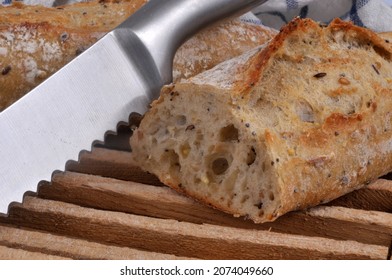 French bread baguette cut on a breadboard with a bread knife close up