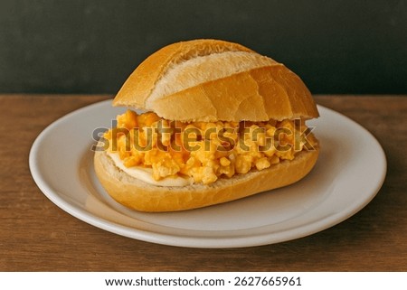 French Bread with deep yellow egg yolk Scrambled Eggs and Mayonnaise on White Plate over Wooden Table