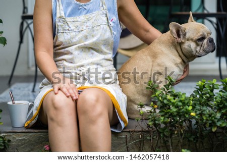 French bulldog is sitting with owner who drinking coffee at the balcony 