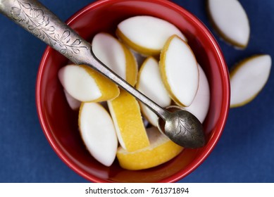 French calissons sweets in a red bowl with an old sugar spoon on blue background.