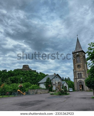French castel and French church in the countryside surrounded by nature and a cloudy sky 