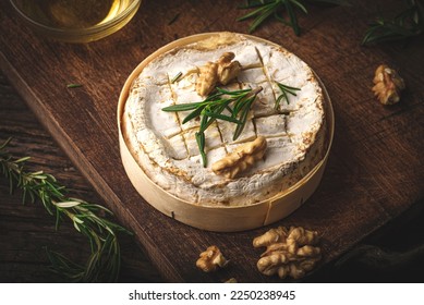 French cheese Camembert baked in a wooden box served with honey, aromatic herbs and nuts. Taste of France, rustic style, 