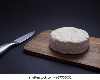 French Saint-Félicien cheese on wooden cutting board isolated on black background 
