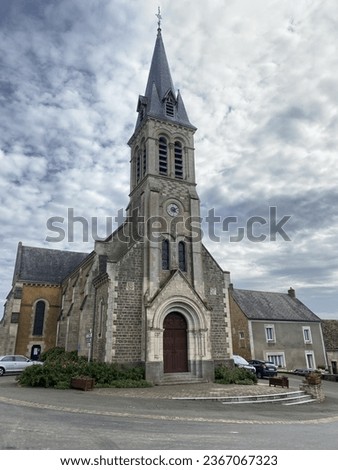 French church with spire with striking clouds behind