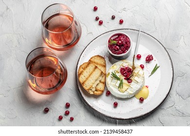 French cuisine. Baked camembert cheese with cranberries and basil leaves, wine on a light background, banner, menu, recipe place for text.