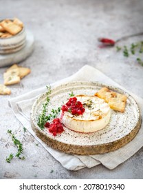 French cuisine. Baked camembert with cranberries. Cheese with berries and thyme. Serving snacks on a plate. French food styling. Brie cheese