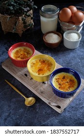 Crème Brûlée Is A French Dessert Made From Egg Yolk, Cream And Sugar Served On A White Ramekin On The Black Marble Table. Noice, Blurry With Grainy Texture. 