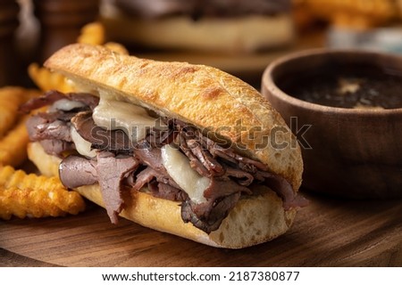 French dip sandwich and french fries with bowl of au jus in background on a wooden platter Stockfoto © 