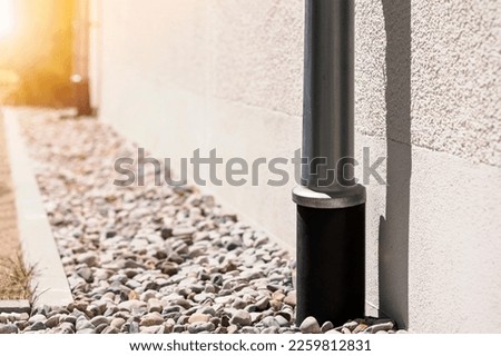 French Drain and Downspout. Drainage System Floor around House. Sewage pipe in Drain Stones Pebble.
