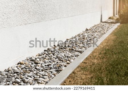 French drain or Drain Rainwater with Drainage Stones or Gravel along House Wall. Drainage System Floor of Modern Exterior Design Building.