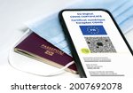 French EU Digital COVID Certificate with the QR code. Translation from french "European COVID digital certificate". Mobile phone over a surgical mask and a french passport. Health passport