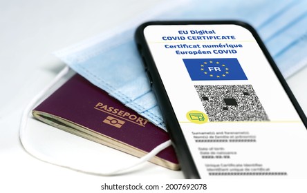 French EU Digital COVID Certificate with the QR code. Translation from french "European COVID digital certificate". Mobile phone over a surgical mask and a french passport. Health passport