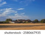 French Farmhouse in Poitou-Charentes Countryside. A picturesque farmhouse nestled in the rolling hills of the Poitou-Charentes region of France, showcasing the idyllic rural landscape with golden fiel