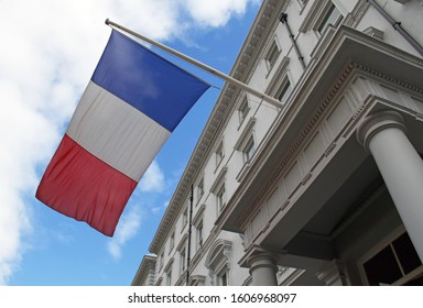 French Flag Against The Blue Sky And White Front Of A Building. London, United Kingdom. Tricolour. 