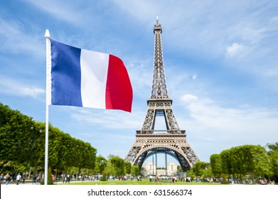 French flag flying in bright blue spring sky in front of the Eiffel Tower in Paris, France