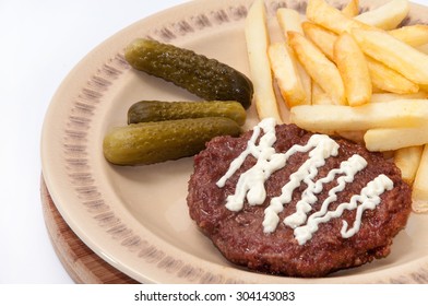 French fries, burger with mayonnaise and pickles served on a plate. - Powered by Shutterstock