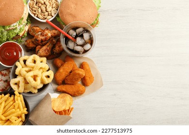 French fries, burgers and other fast food on white wooden table, flat lay with space for text - Powered by Shutterstock