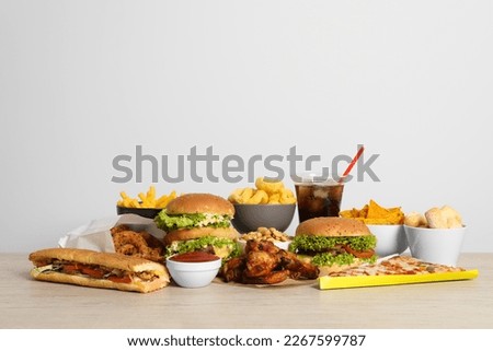 French fries, burgers and other fast food on wooden table against white background