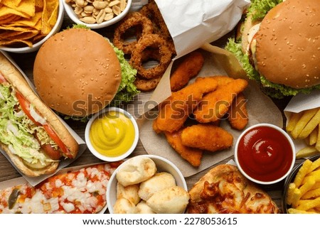 French fries, burgers and other fast food as background, top view