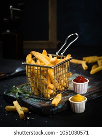 French fries close up with condiments on dark background