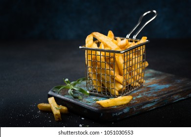 French fries close up with salt and rosemary on dark background