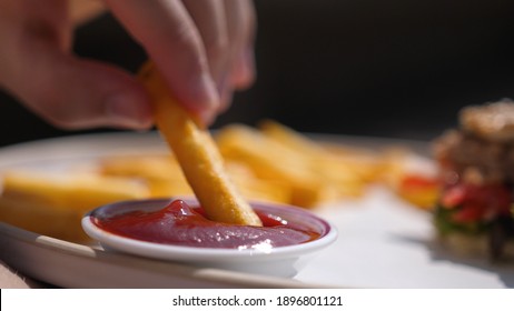 French Fries Is Dipping In Red Tomato Sauce. Eating French Fries, Potato Chips With Ketchup. Junk Food, Fast Food Concept