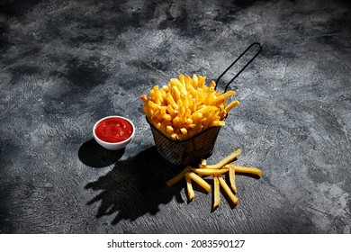French fries in fryer basket on dark background