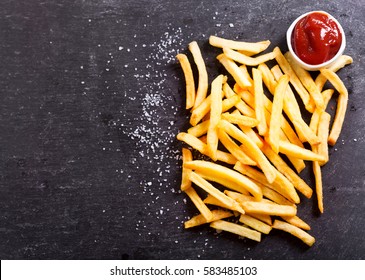 French fries with ketchup on dark table, top view - Shutterstock ID 583485103