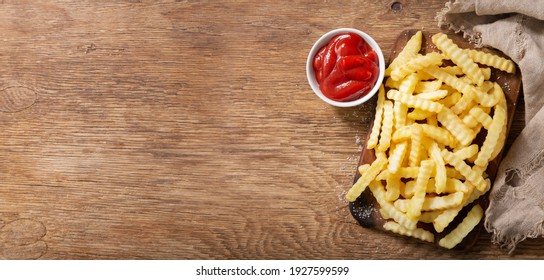 French fries with ketchup on a wooden background, top view