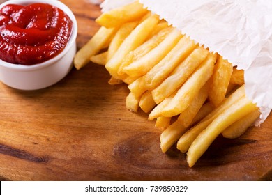 French fries with ketchup on wooden board