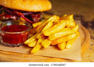 French Fries & Ketchup Sauce Served On Wooden Plate In American Fast Food Restaurant For Dinner.Tasty Unhealthy Fastfood For Snack In Diner Cafe.Bad Diet With High Cholesterol And Saturated Fat