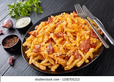 French Fries With Melted Mix Of Shredded Cheese And Bacon Served On A Plate On A Black Wooden Table With Ranch Dressing In A Gravy Boat, View From Above, Close-up