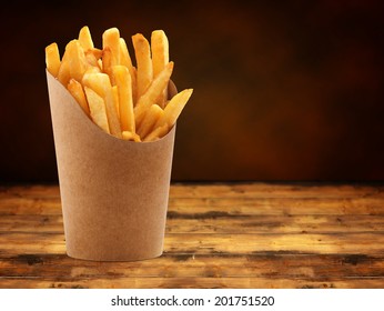 french fries in a paper basket on wooden table