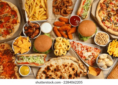 French fries, pizza and other fast food on wooden table, flat lay - Powered by Shutterstock