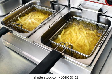 French fries or potato chips deep frying in oil in a commercial metal fryer in a restaurant as an accompaniment to meals - Powered by Shutterstock