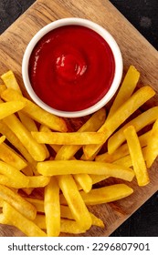 Patatas fritas francesas, bocadillos de patata con ketchup, comida rápida en una tabla de madera, perdigones sobre planchas