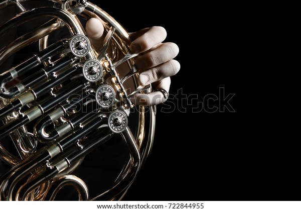 French horn instrument. Hands playing horn player\
close up isolated on\
black