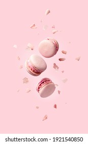 French macarons flying in the air among the crumbs on pink background. Levitation concept. food background. Pastel color. deconstruction food.
