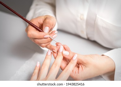 französische Maniküre. Manicure Meister, weiß lackieren auf der Nagelspitze mit einer dünnen Bürste, Nahaufnahme